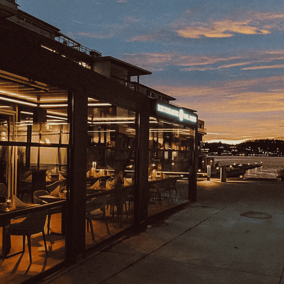 Solnedgang over en bryggerestaurant som er innglassert med vinduer