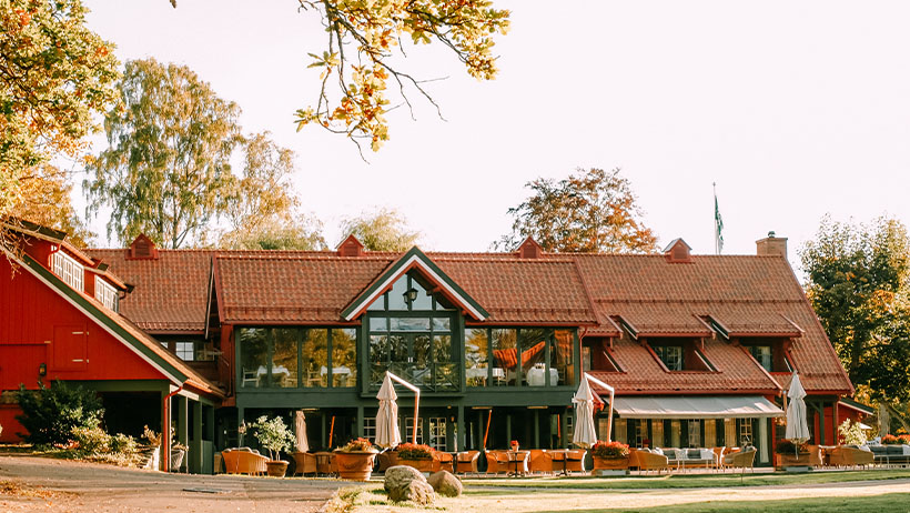 Et grønt gårdshus med terrasse i høstsol