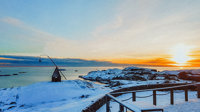 snødekt landskap foran sjø med gammeldags fyr i stein