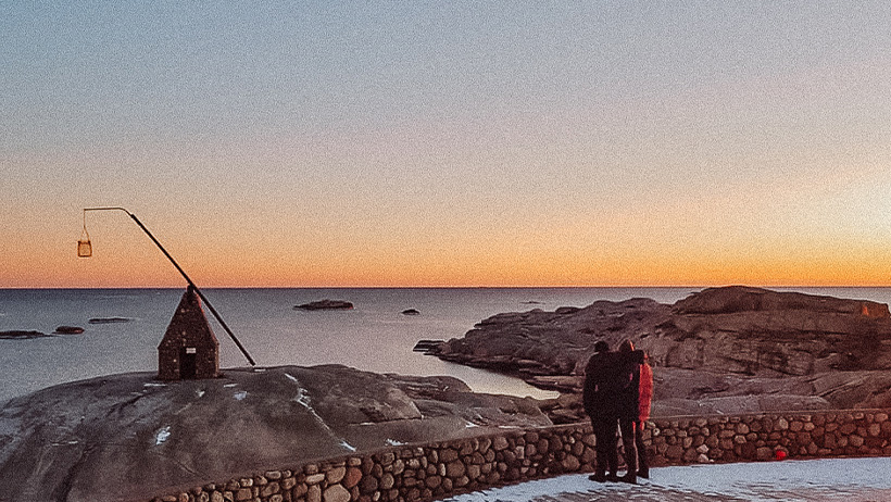 to personer ser på solnedgangen med et gammeldags stein fyr foran de