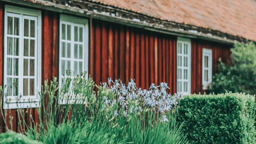 Rødt trehus med planter foran