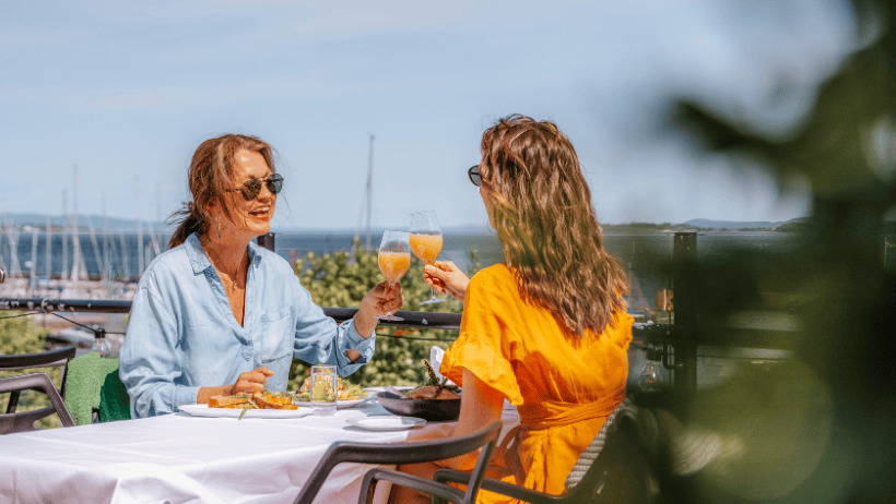to personer sitter på en utendørsterrasse og skåler