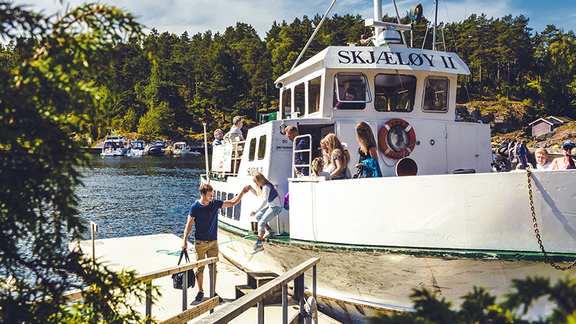 Rutebåt med passasjerer ligger til kai og personer går i land