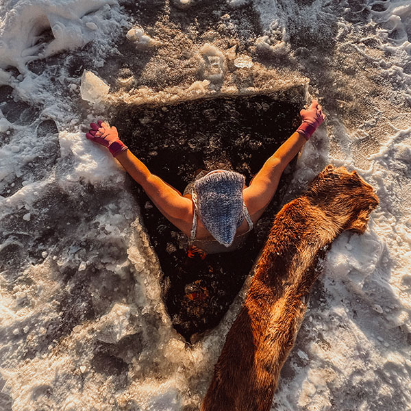 person bader på vinteren i et hull i isen