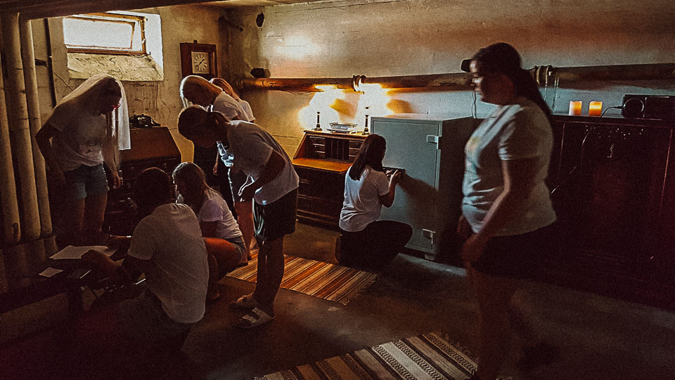 mennesker i et rom med ulike møbler som prøver å løse en gåte