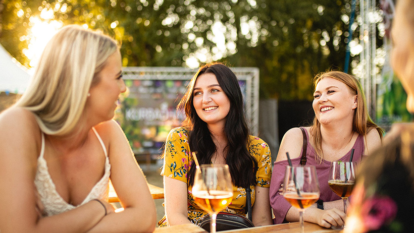 tre personer sitter ved et bord og drikker
