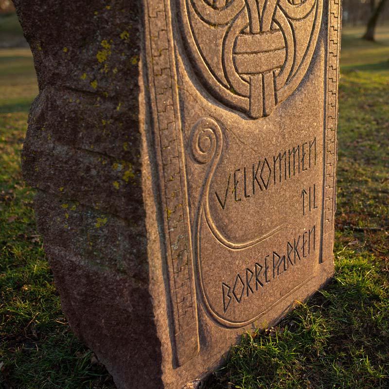Velkomststein: Steinplate med inngravert tekst "Velkommen til Borre" i naturlig omgivelse.