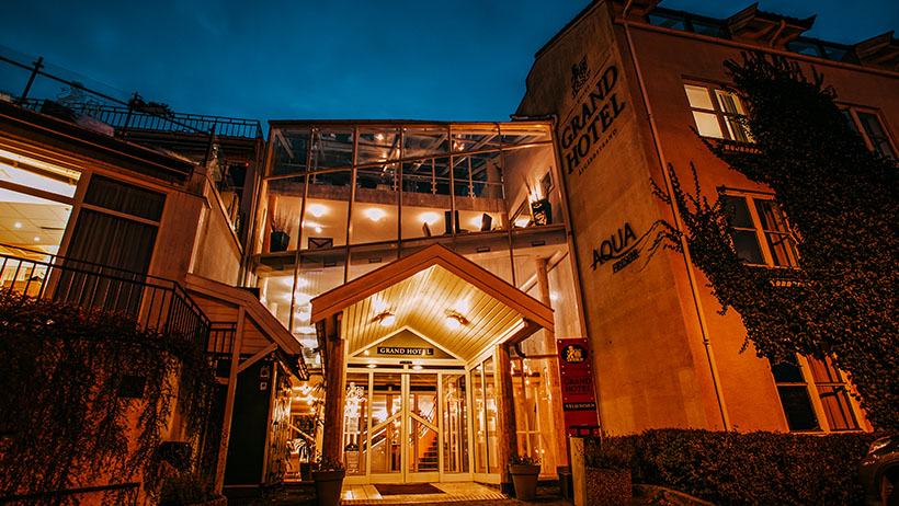 Grand Hotel i Åsgårdstrand på kveldstid, med lysende inngang og vakker arkitektur.