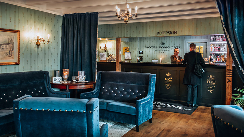 Hyggelig og tradisjonell hotellresepsjon med møbler i mørkeblå fløyel, Hotel Kong Carl.