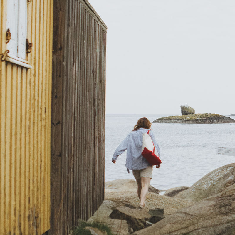 Person går tur ned til sjøen med strandbag over skulderen