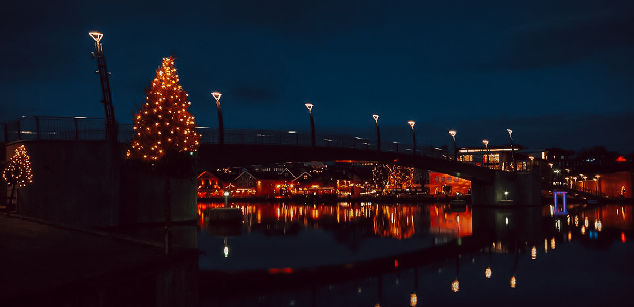 Bro med julelys speiler seg i vannet