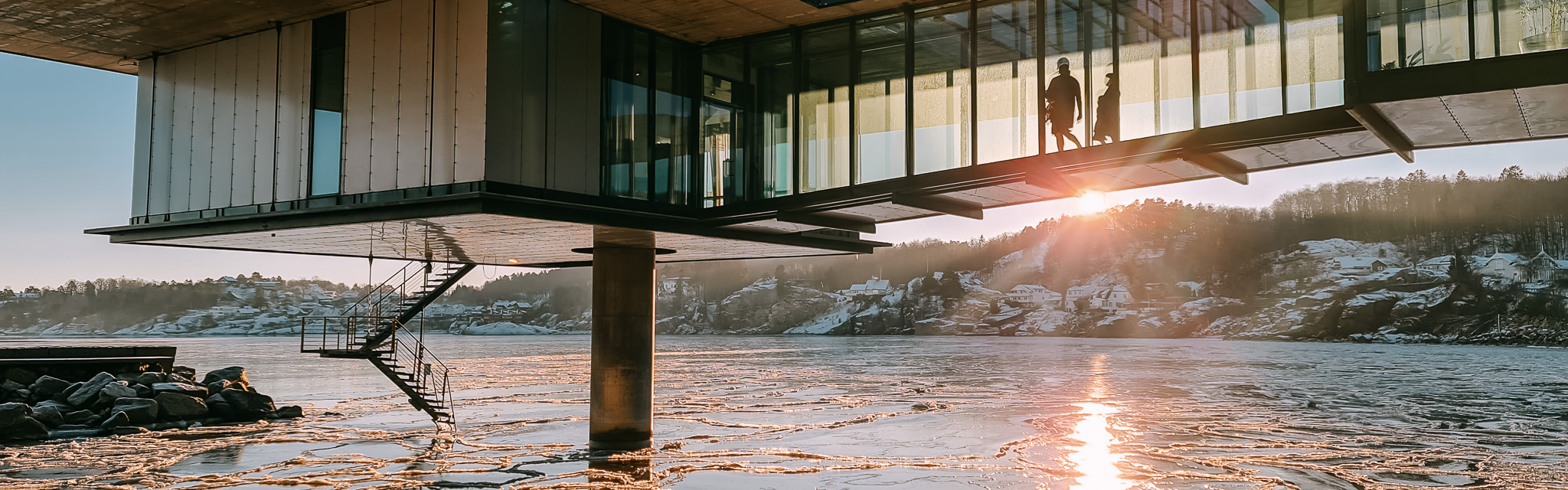 sjø med isflak og bygning hvor folk går inne.