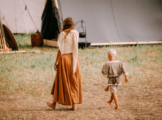 Voksen og barn i vikingdrakter på Midgard vikingsenter i Horten