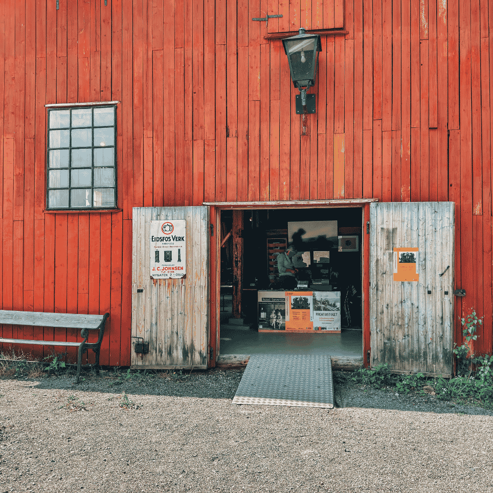 a red wooden wall with double doors wide open and a bench on the left