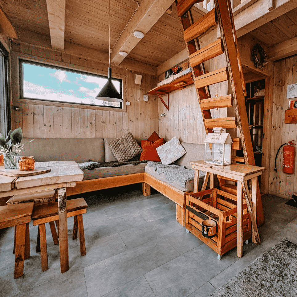 Living room with a built-in corner sofa, a staircase leading up to the loft and a fire extinguisher on the wall.