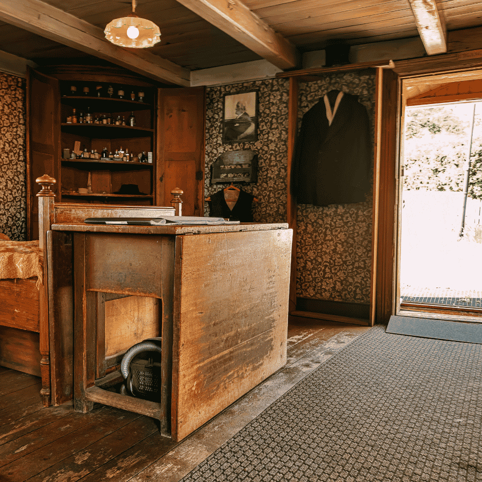 A room with an old bed, a wallpapered wall, a wardrobe and a medicine cabinet containing bottles.