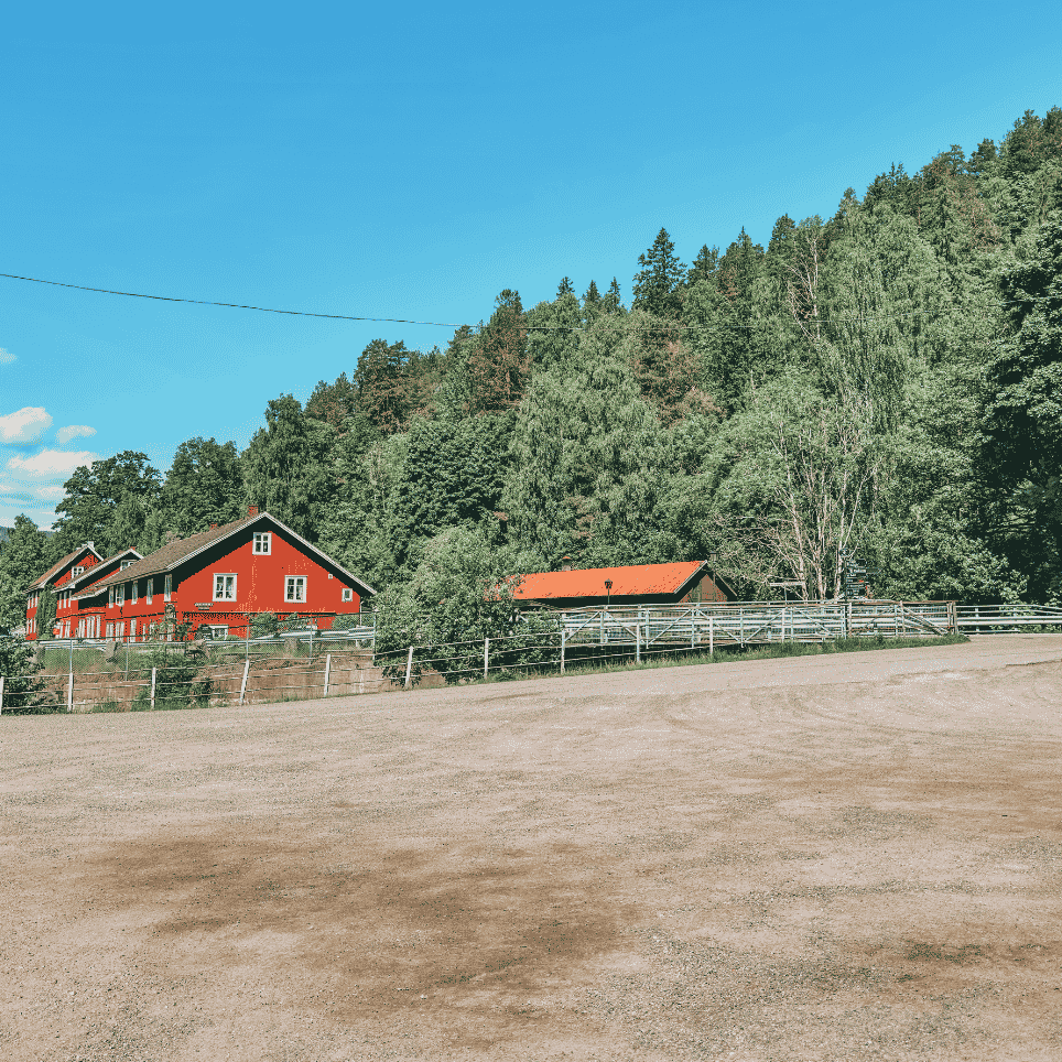 a red wooden house with a large gravel area in the foreground