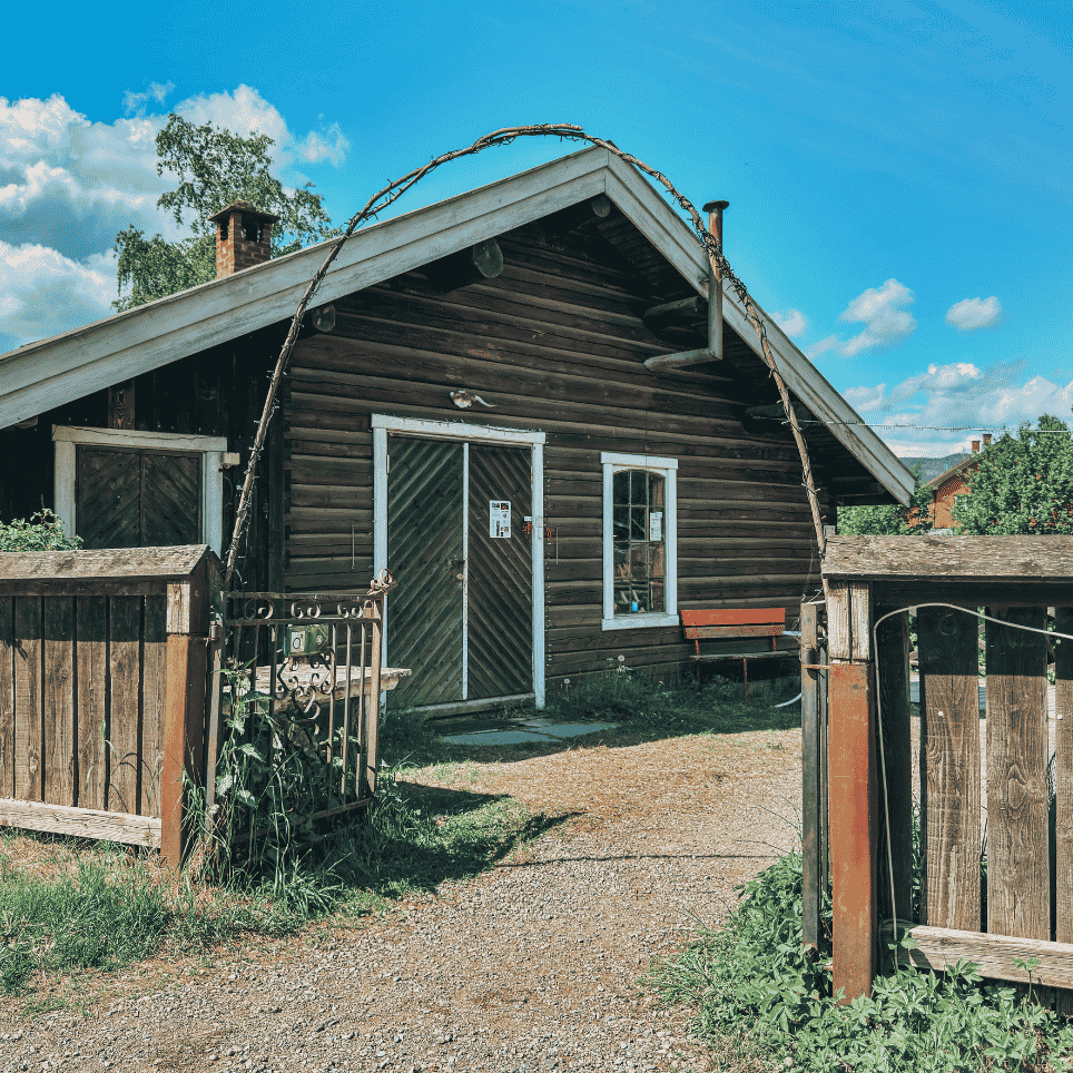 a brown wooden house with an open entrance to the garden